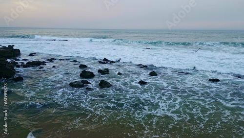 Cloudy ocean splashing cliffside nature at beach closeup. Waves covering rocks