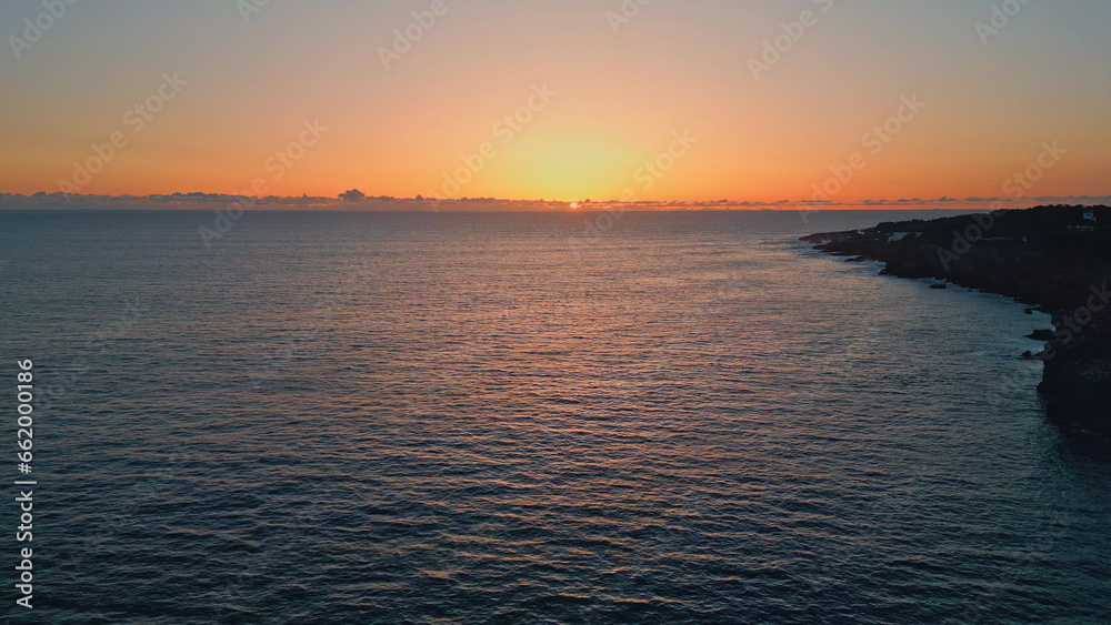 Sunset sea rippling water beach aerial view. Golden sky calm marine surface 