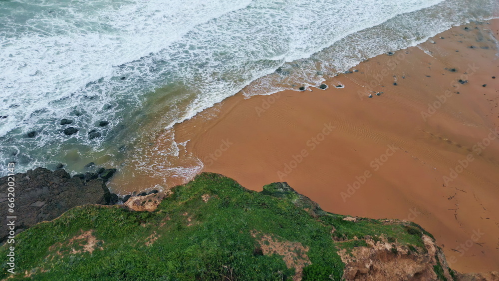 Aerial view green woodland hills sandy beach. Foaming ocean surf at cloudy day