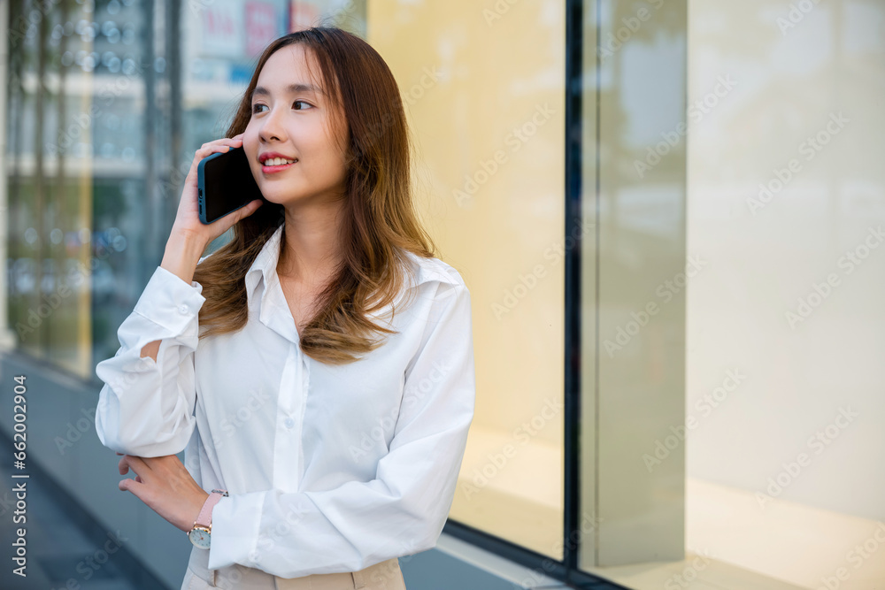 Smiling brunette boss talking on cell phone with client. Business woman in white shirt using mobile phone in city street. Phone conversation for work is modern communication technology. Smiling brunette boss talking on cell phone with client. Business woman in white shirt using mobile phone in city street. Phone conversation for work is modern communication technology.