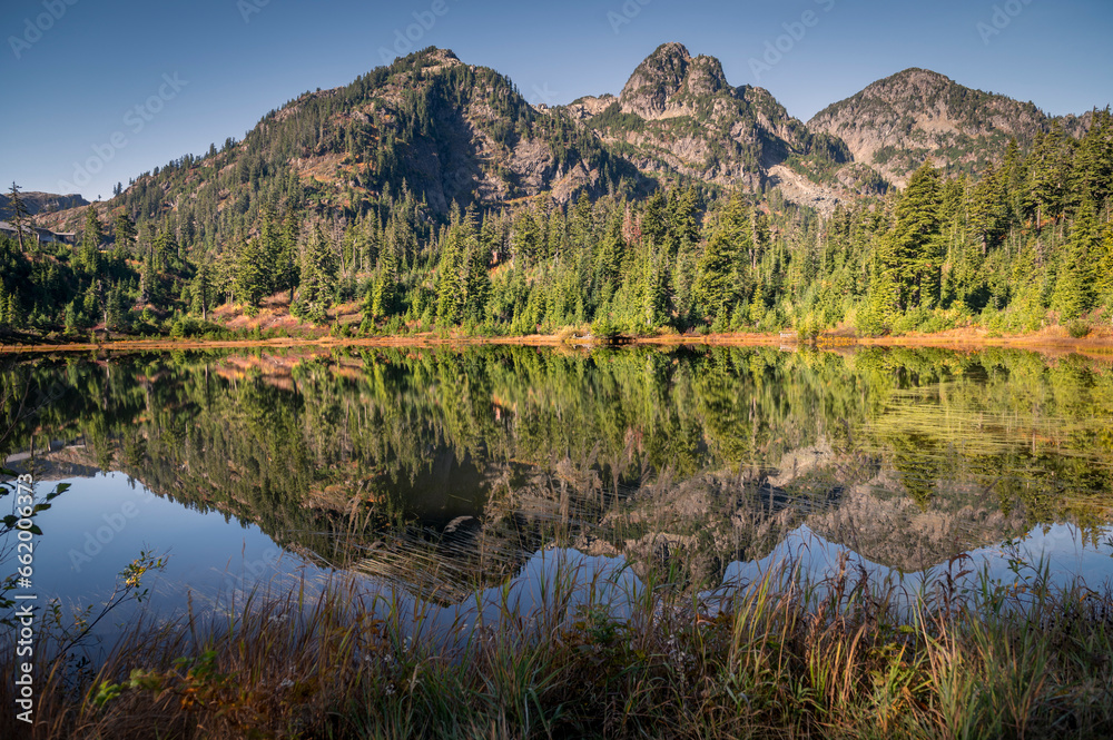 Cascade Mountains reflected in the still waters of Picture Lake in the Mt. Baker Forest. Fall colors add to the beauty of this alpine environment in the area known as Heather Meadows Washington state.