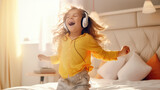 Cute smiling toddler girl wearing headphones having fun in the bedroom of the house. The girl listen music, dances, jump and sing.