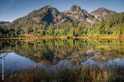 Cascade Mountains reflected in the still waters of Picture Lake in the Mt. Baker Forest. Fall colors add to the beauty of this alpine environment in the area known as Heather Meadows Washington state.