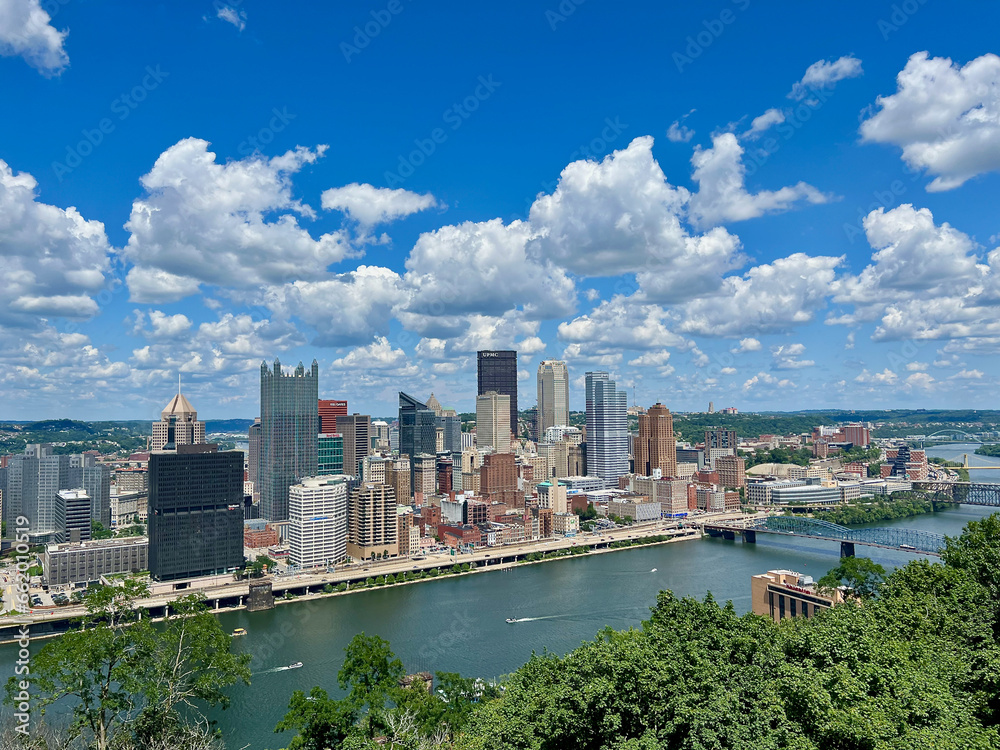 Distant view of downtown Pittsburgh along the Ohio River with blue summer skies.