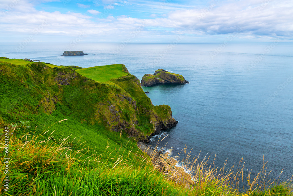 A wide view of the Carrick-a-Rede Rope Bridge, a rope bridge near Ballintoy in County Antrim, Northern Ireland. The bridge links the mainland to the tiny island of Carrickarede.