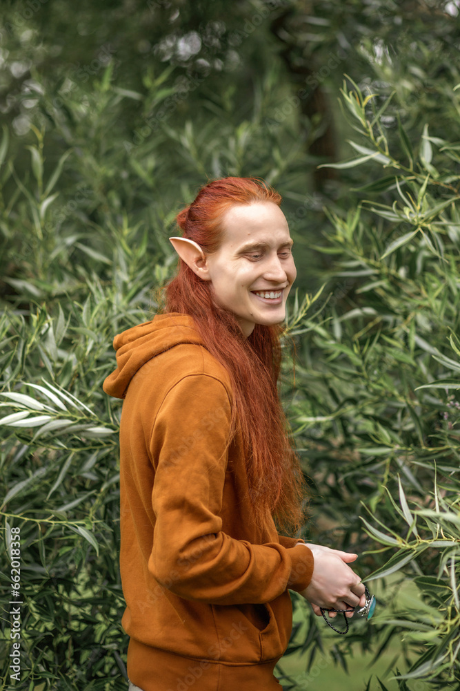 Artistic elf man with red hair and green eyes in the forest