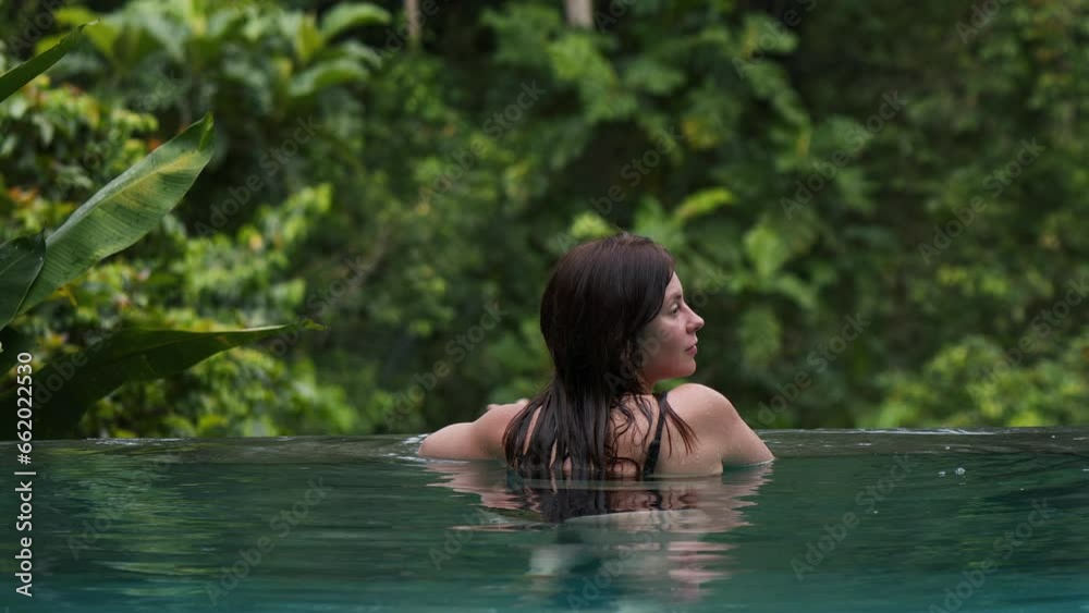 Attractive woman resting on the edge of infinity swimming pool, Rain in tropical forest, jungle, concept of tranquility, copy space. Attractive woman resting on the edge of infinity swimming pool, Rain in tropical forest, jungle, concept of tranquility, copy space.