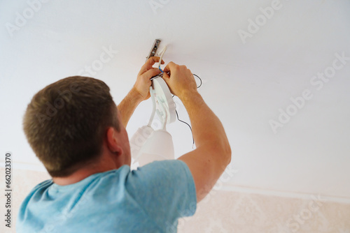 A man is working on the installation of a ceiling luminaire on the ceiling.