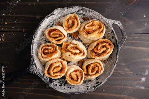 Unbaked Cinnamon Rolls in a Floured Cast-Iron Skillet: Raw cinnamon rolls layered with cinnamon, brown sugar, and crumbled bacon
