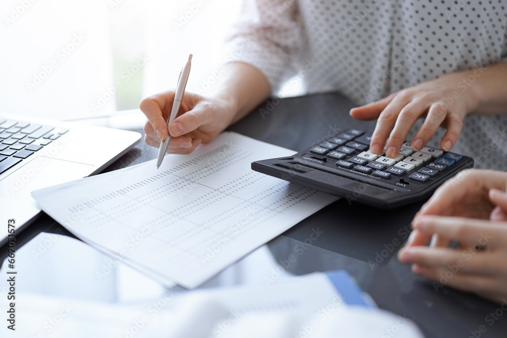 Woman accountant using a calculator and laptop computer while counting taxes for a client. Business audit concepts Woman accountant using a calculator and laptop computer while counting taxes for a client. Business audit concepts