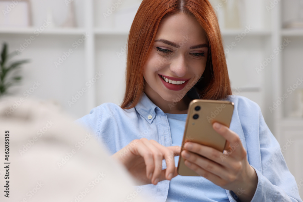 Happy woman sending message via smartphone on couch at home Happy woman sending message via smartphone on couch at home