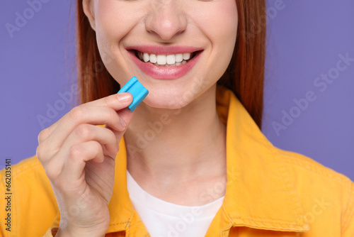 Woman with bubble gum on purple background, closeup