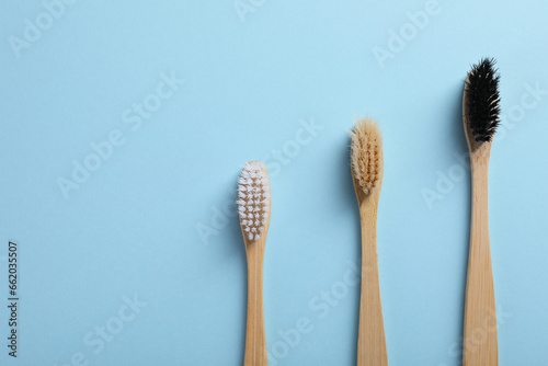 Bamboo toothbrushes on light blue background  flat lay. Space for text