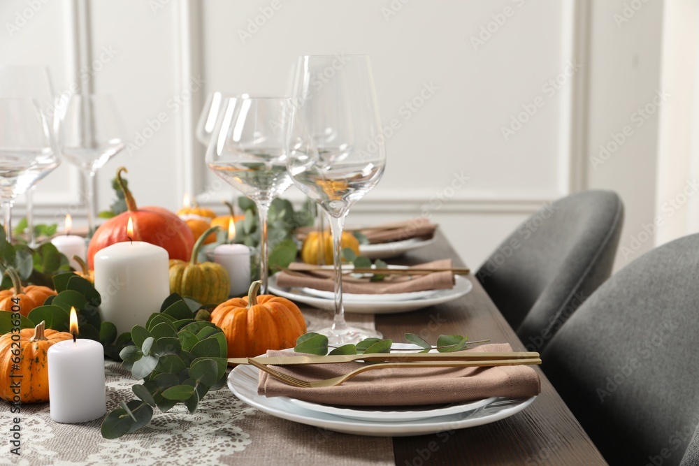 Fototapeta premium Beautiful autumn table setting. Plates, cutlery, glasses, pumpkins and floral decor
