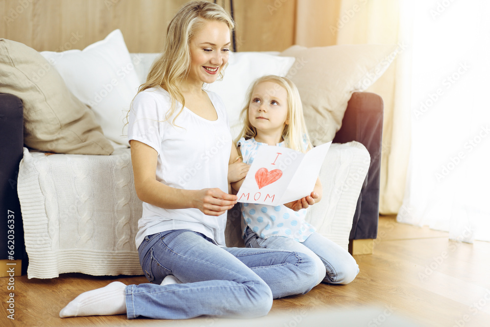 Happy mother day in sunny flat. Child daughter congratulates mom and gives her postcard with heart drawing. Family concept Happy mother day in sunny flat. Child daughter congratulates mom and gives her postcard with heart drawing. Family concept