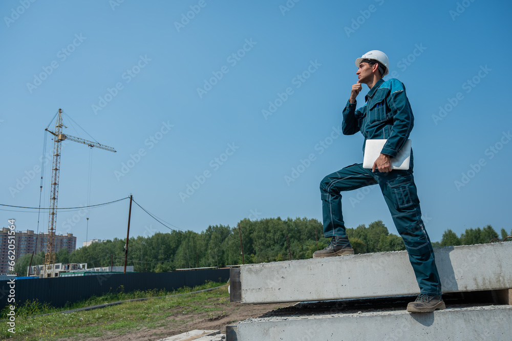 Caucasian male builder in hardhat holding laptop at construction site. Caucasian male builder in hardhat holding laptop at construction site.