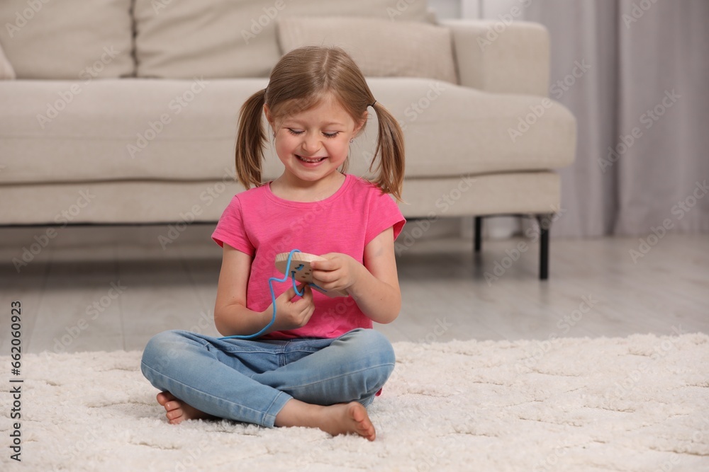 Cute little girl playing with wooden lacing toy indoors Cute little girl playing with wooden lacing toy indoors