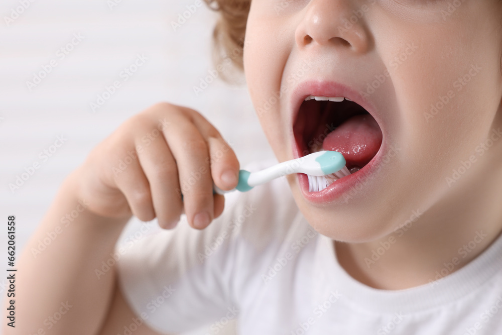 Little boy brushing his teeth with plastic toothbrush on white background, closeup Little boy brushing his teeth with plastic toothbrush on white background, closeup
