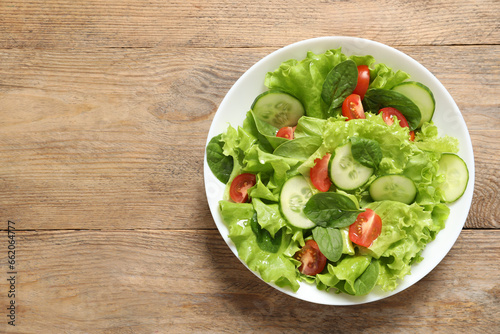 Delicious salad in bowl on wooden table, top view. Space for text
