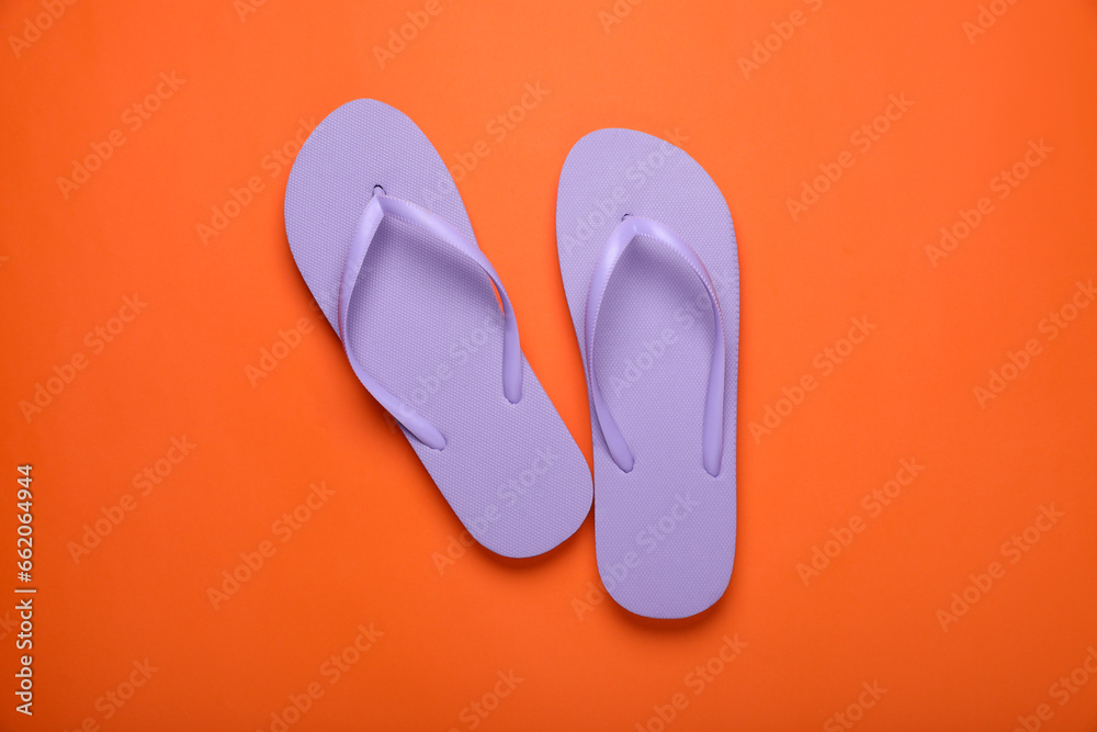 Stylish violet flip flops on orange background, top view Stylish violet flip flops on orange background, top view