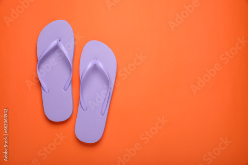 Stylish violet flip flops on orange background, top view. Space for text