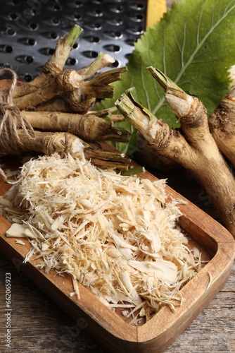 Grated horseradish and roots on wooden table, above view
