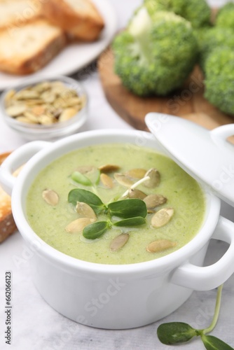 Delicious broccoli cream soup with pumpkin seeds on white marble table, closeup. Space for text