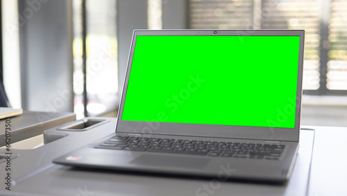 Open laptop with a blurry background and a green screen. photo