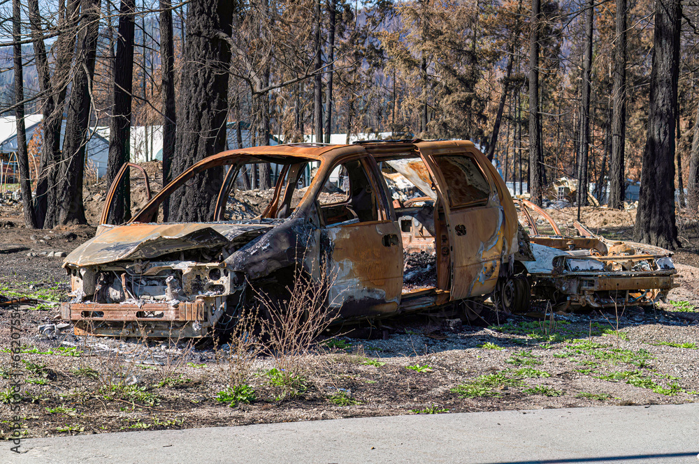 A partially burned van and another car awaits final disposal after the Lower East Adams Lake Wildfire in the North Shuswap, B.C. Canada.