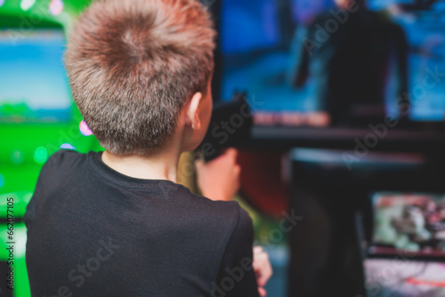 Kids play slot machine at amusement theme park, children play arcade gaming machine, racing and shooting game at the fair, teenagers having fun playing simulator video games