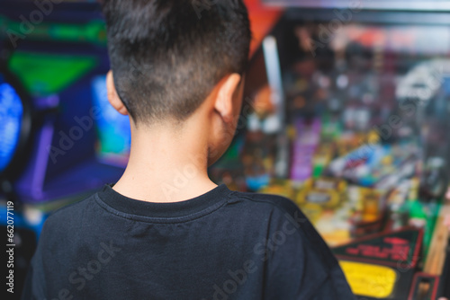 Kids play slot machine at amusement theme park, children play arcade gaming machine, racing and shooting game at the fair, teenagers having fun playing simulator video games