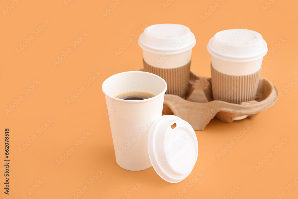 Takeaway paper cups of tasty coffee and holder on beige background Takeaway paper cups of tasty coffee and holder on beige background
