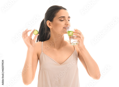 Young woman drinking cucumber water on white background