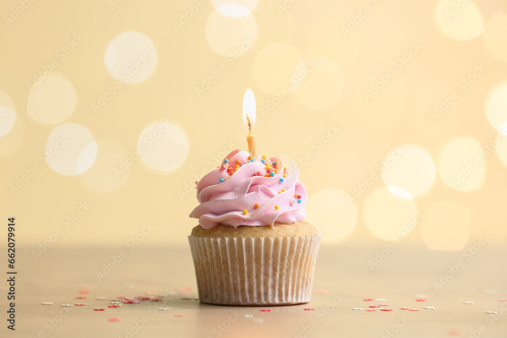 Tasty Birthday cupcake with burning candle on table against blurred lights Tasty Birthday cupcake with burning candle on table against blurred lights