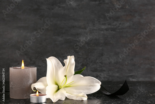 Beautiful lily flower and burning candle on black table