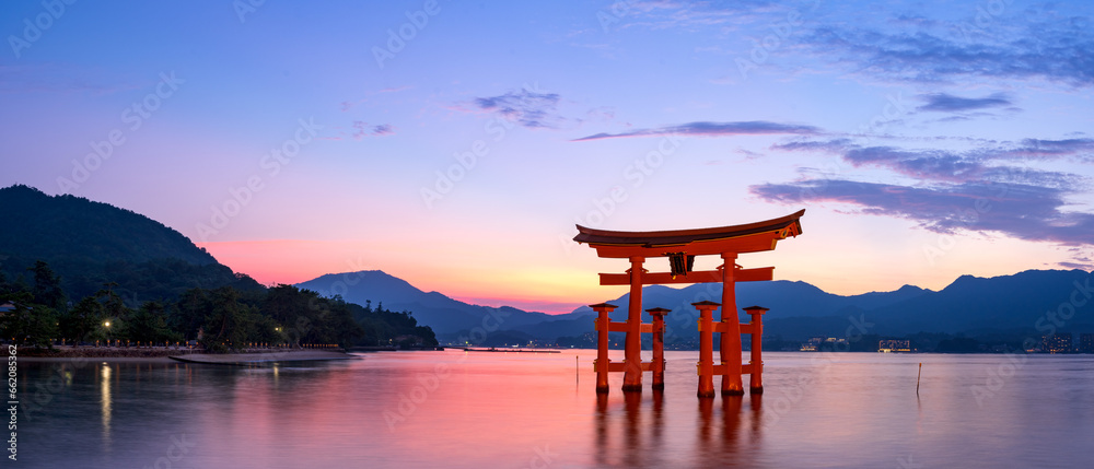Panoramic view of Itsukushima Shrine's torii gate at Miyajima in Hiroshima at magic hour. - obrazy, fototapety, plakaty 