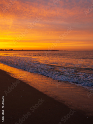 Amazing view of a fiery sunrise with multicolored clouds. Sea waves along the seashore at sunrise. Morning time. Ocean view. La Baule-Escoublac, France