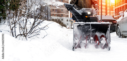 snowblower removes snow, a man cleans the yard outside photo