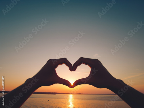 A heart shpa made with 2 hands  with an open natural cloudy background representing the open sea