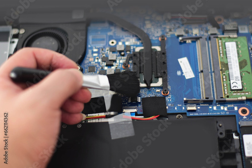omputer technician Laptop motherboard repairman is using a converter to clean the motherboard.