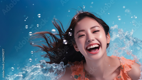 Smiling chinese woman wearing swimsuit playing water splash © pariketan