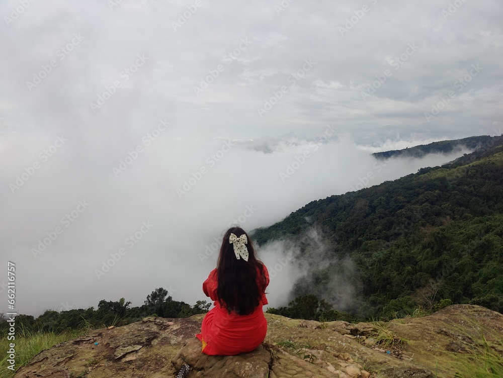 The person is dressed in red clothing. It seems to be taken in a hill station or highland area, possibly while hiking. The person is dressed in red clothing. It seems to be taken in a hill station or highland area, possibly while hiking.