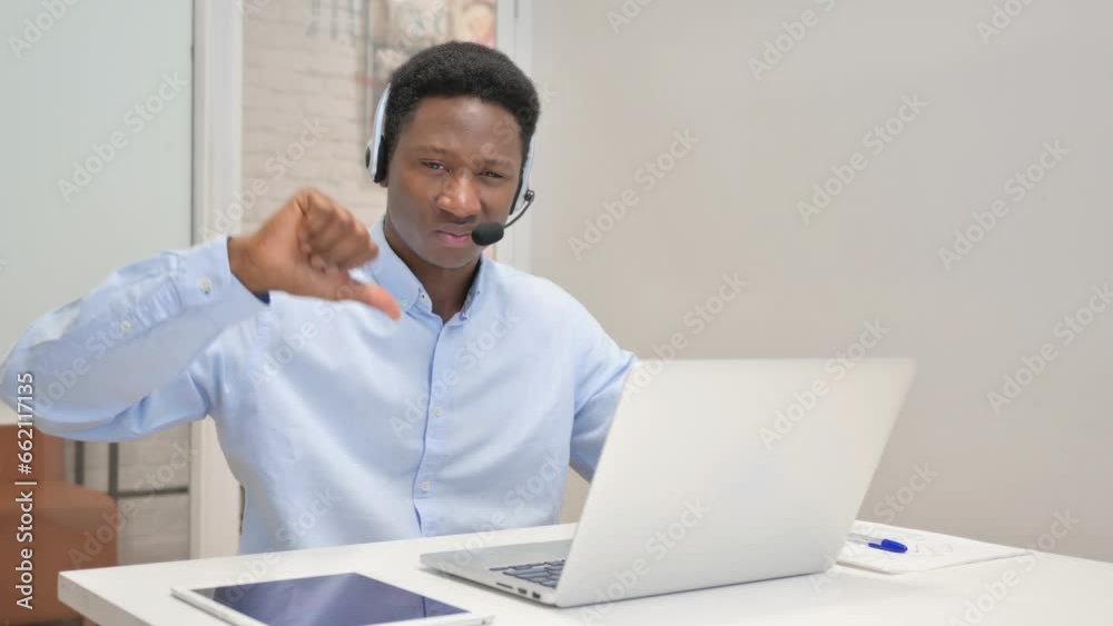 Thumbs Down by African Man with Headset Using Laptop in Call Center Thumbs Down by African Man with Headset Using Laptop in Call Center