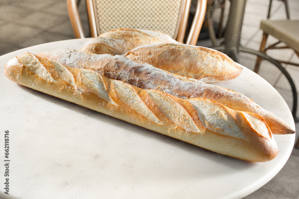A view of a patio table full of several French baguettes.