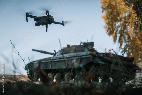 drone flying above the tank in the background in nature. help of reconnaissance drones in modern warfare.
