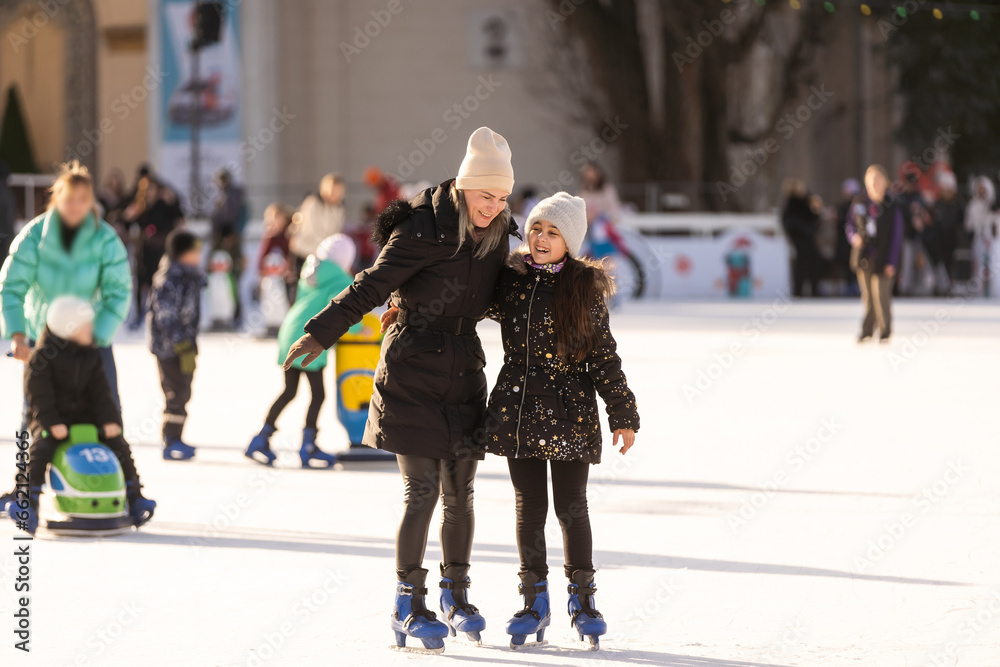 Mother with her daughters skates on ice skating