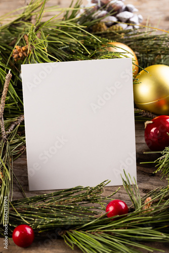 Vertical image of christmas decorations, white card and copy space on wooden background