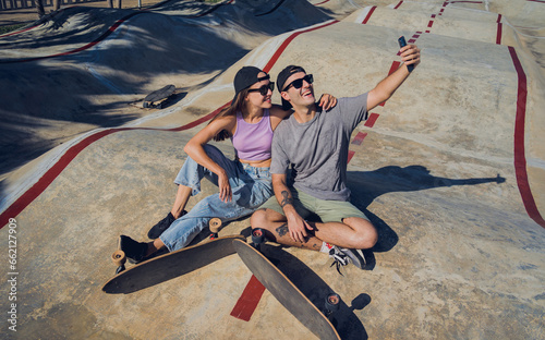 Young happy couple with skateboards taking selfie at the skatepark