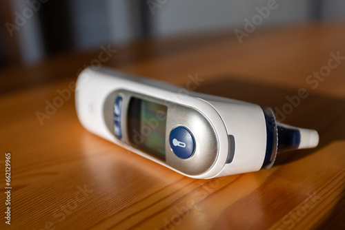 Digital ear thermometer on a wooden desk - shallow DOF