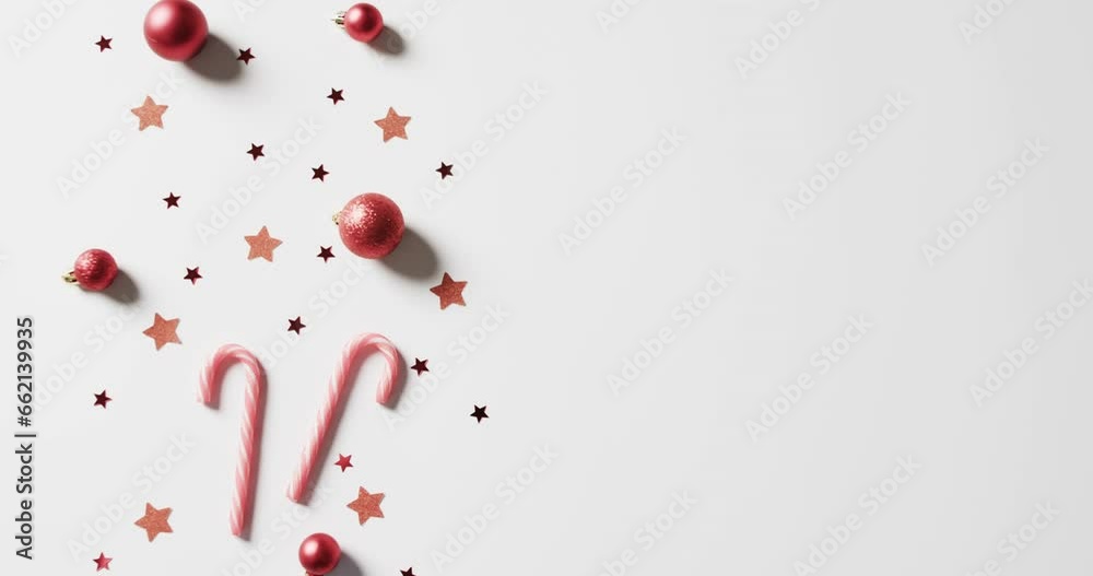 Video of baubles, candy canes and stars christmas decorations with copy space on white background Video of baubles, candy canes and stars christmas decorations with copy space on white background